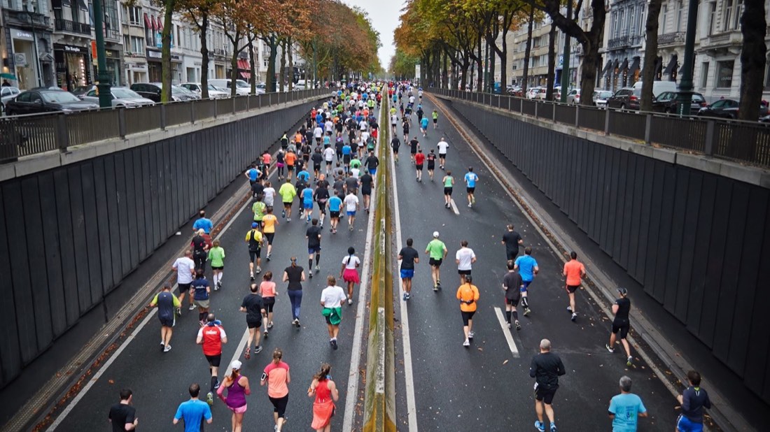 Runners on a road during a mass-participation race — the shape of a European 10K weekend